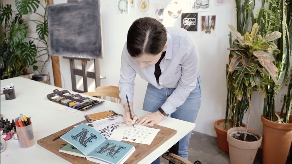 How to overcome doubt on your creative journey. Image of woman lettering in her studio.